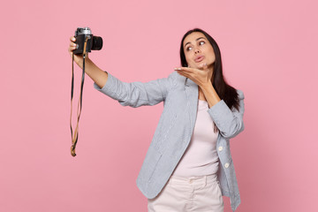 Wall Mural - Tender pretty young woman doing selfie shot on retro vintage photo camera, blowing sending air kiss isolated on pink pastel background. People sincere emotions lifestyle concept. Mock up copy space.