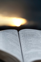 Open Bible With Stunning Sunset In The Background. Close-up. Vertical Shot.