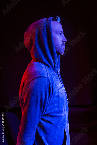 Fotografía A male model with stubble wearing a hood up in a dark atmospheric future colour setting