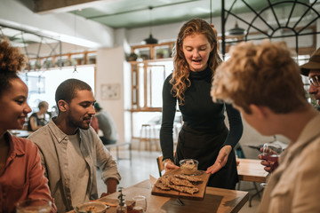 Wall Mural - Smiling waitress bringing food to a table of customers