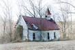 An old country church with a red metal roof, stands in disrepair on a back road in rural Tennessee.