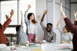 © Seventyfour - Multi-ethnic team of young businesspeople  raising hands celebrating success in office, copy space