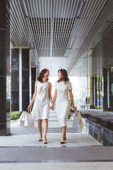 Wall Mural - Two woman friends shopping together and talking.