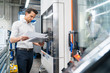 © Westend61 - Businessman reading manual at a machine in a factory
