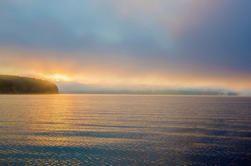 Wall Mural - colorful misty sunrise, sunset over the river, the silhouette of the shore with the forest.