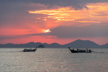 Wall Mural - Picturesque seascape view with thai local long-tail boats floating in water at beautiful sunset on sea