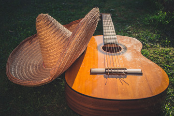 Wall Mural - Acoustic guitar lying on the grass with sombrero hat on top of it. Cinco de Mayo concept