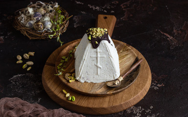 Paskha (Pasha) with pistachios decorated with chocolate glaze and pistachios. Traditional Russian orthodox Easter quark dessert. Easter food background. 