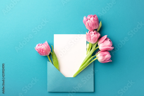 Bouquet of pink tulips in turquoise envelope on turquoise background. Mockup ...
