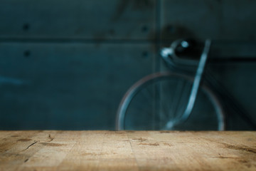 Empty Wooden Table in Front of Blurred Background of Living Room with a Blue Bicycle Near the Window. Mock Up for Display of Product. Blank for Your Layout