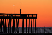 Tall Pier Agains A Beautiful Orange And Yellow Sky Just Before Sunrise. Photo By: Chuck Beyer