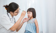© paulaphoto - Asian doctor woman examine eyes of little asian girl in the clinic.  Senior looks in instrument for checking eyes at ophthalmologist. Health care and medical for young toddler kid concept.