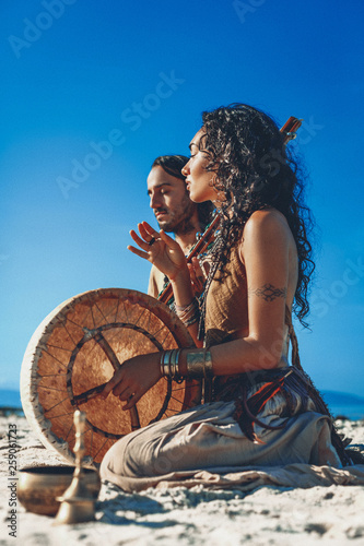 Plakat beautiful young couple playing ethnical music with shaman drums outdoors