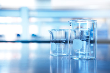 Wall Mural - two glass beaker on chemistry science laboratory table blue research and education background