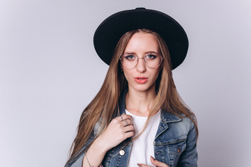 Beautiful caucasian young cheerful hipster stylish girl model in black hat isolated on grey background. Fashion, professional model, style concept 