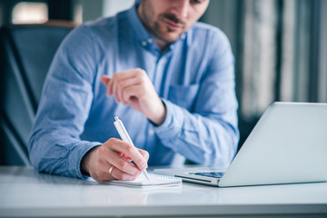 Businessman writing on a note pad with a pen in the office.