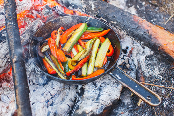 A dish of red bell peppers and cucumbers in a pan on a fire