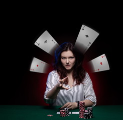 Brunette actress girl plays cards over green cloth posing on a dark background in blue and red light.