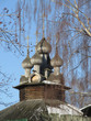 Wooden church in Kostroma, Russia on the spring blue sky background seen through the trees