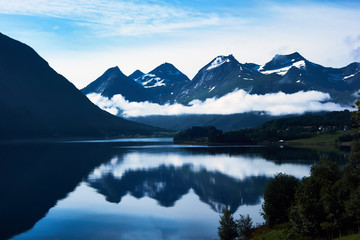 Beautiful blue landscape with snow-capped mountains and thier reflection in water