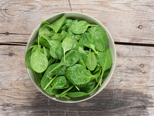 Wall Mural - Fresh spinach leaves in bowl on rustic wooden table