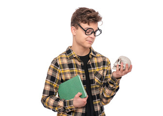 Poster - Handsome Student Teen Boy in Eyeglasses with Books and small skull. Portrait of School Teenager holding books, isolated on white background. Happy smiling college child.