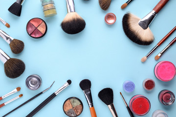 makeup brushes on a blue background. Top view, flat lay, copy space