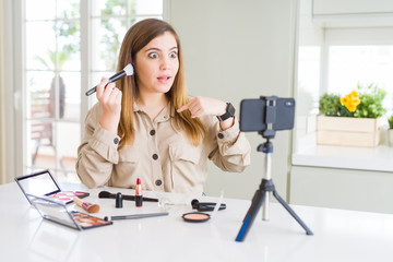 Poster - Beautiful young influencer woman recording make up video tutorial with surprise face pointing finger to himself