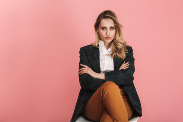 Sticker - Photo of serious businesswoman sitting in chair and looking on camera isolated over pink background