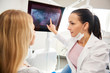 © gpointstudio - Female dentist pointing at patient's x-ray