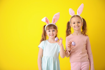 Wall Mural - Cute little children with Easter eggs and bunny ears on color background