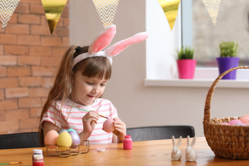 Wall Mural - Cute little girl painting Easter eggs at home