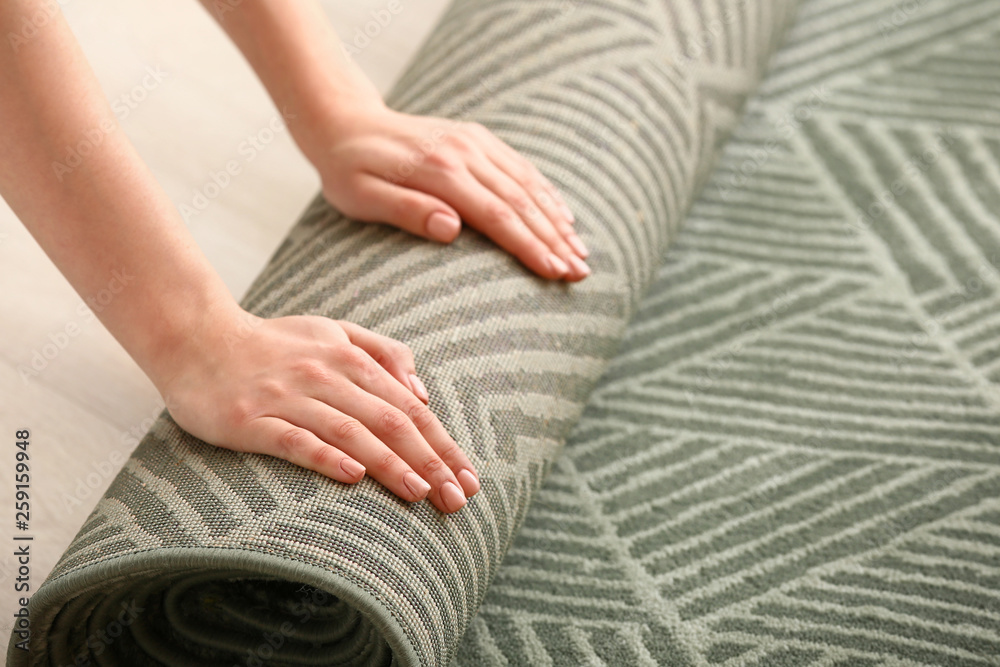 Woman rolling carpet on floor in room
