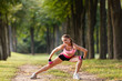 © Olga Mishyna - sport girl making exercises outdoors. Young sport woman in a park. Sport and fitness on open air. Exercise lunge leg on the grass and stretching