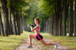 © Olga Mishyna - sport girl making exercises outdoors. Young sport woman in a park. Sport and fitness on open air. Exercise lunge leg on the grass and stretching