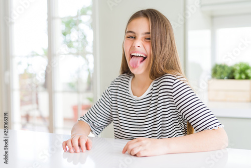 Cuadros en Lienzo Beautiful young girl kid wearing stripes t-shirt sticking tongue out happy with funny expression