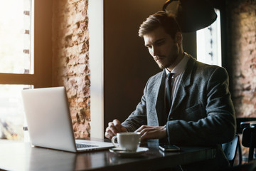 Young businessman working on a plan of Internet project on the laptop. Man discusses business matters by phone. Working computer for internet research. Digital marketing. Development