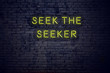 Positive inspiring quote on neon sign against brick wall seek the seeker