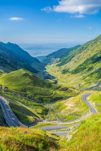 Transfagarasan road in the Carpathian Mountains, Transylvania, Romania, Eastern Europe. Alpine landscape with green meadows, grass, valley and blue sky. Famous tourist attraction worldwide.