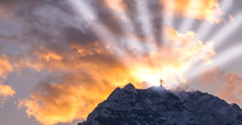 Silhouette Of A Cross On The Top Of A Mountain With Sun Rays And Dramatic Clouds In The Background. Symbol Of God, Religion, Resurrection,miracle And Faith. 