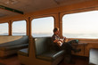 © ML Harris - Happy, smiling, creative, independent middle aged man solo traveler ferry passenger looking out window and playing guitar. Adventure, fulfillment, journey concepts.