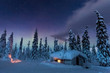 © Satu Juvonen - Light shines through window in snow covered cabin under colorful night sky