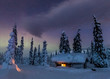 © Satu Juvonen - Light shines through window in snow covered cabin under colorful night sky