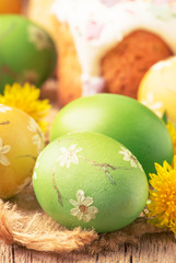 Easter green and yellow painted eggs, yellow dandelion flowers on spring festive composition in rustic style, russian orthodox tradition, vintage wooden background, selective focus