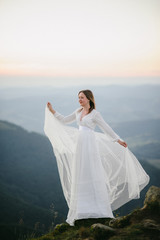 Wall Mural - woman in a wedding dress runs across the field toward the mountains