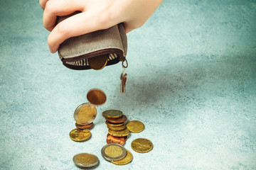 Several coins fall on the table from an empty wallet in a woman's hand, poverty, crisis, bankruptcy and financial problems concept