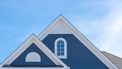 white attic window vent on blue siding, gable, corbel, louver on a new construction luxury american 