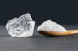 Pure natural white crystal bath or rock salt with food or sea salt in wooden spoon on wooden background