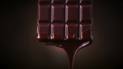 Wall Mural - Chocolate bar with melted dark chocolate dripping over dark brown background. Confectionery concept backdrop. Melted premium chocolate flowing. Sweet dessert. 4K UHD video, slow motion