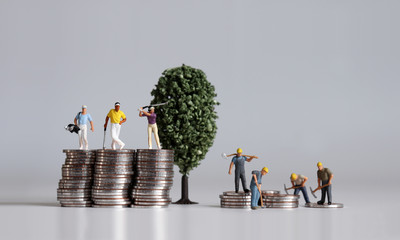 Wall Mural - Miniature people standing on a pile of coins. Concepts about the lives of the rich and the poor.